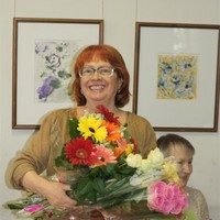 Виктория Полищук с цветами на фоне своих работ